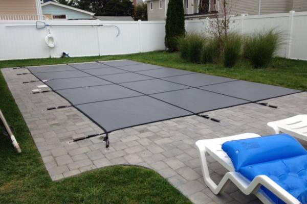 A Garrett pool safety cover over an inground pool - Melchiorre Gray Mesh Kessler
